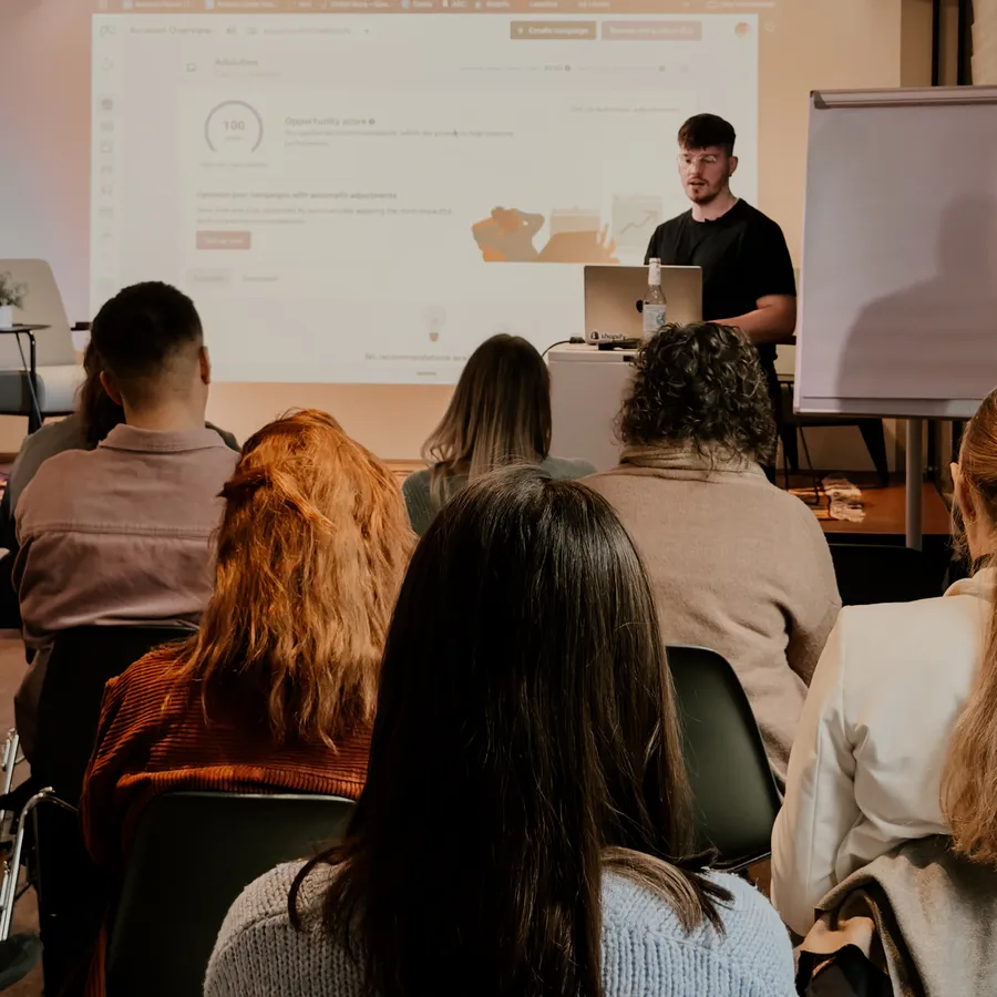 Alex steht bei einem Workshop vor Publikum, hinter ihm die Leinwand mit einem Werbekonto
